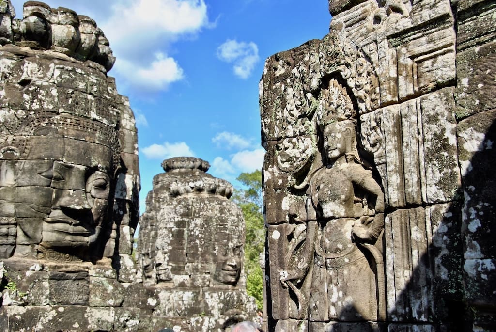 A beautiful photo of Bayon Temple on a sunny day featuring a few of the Gothic Towers and the face statues.