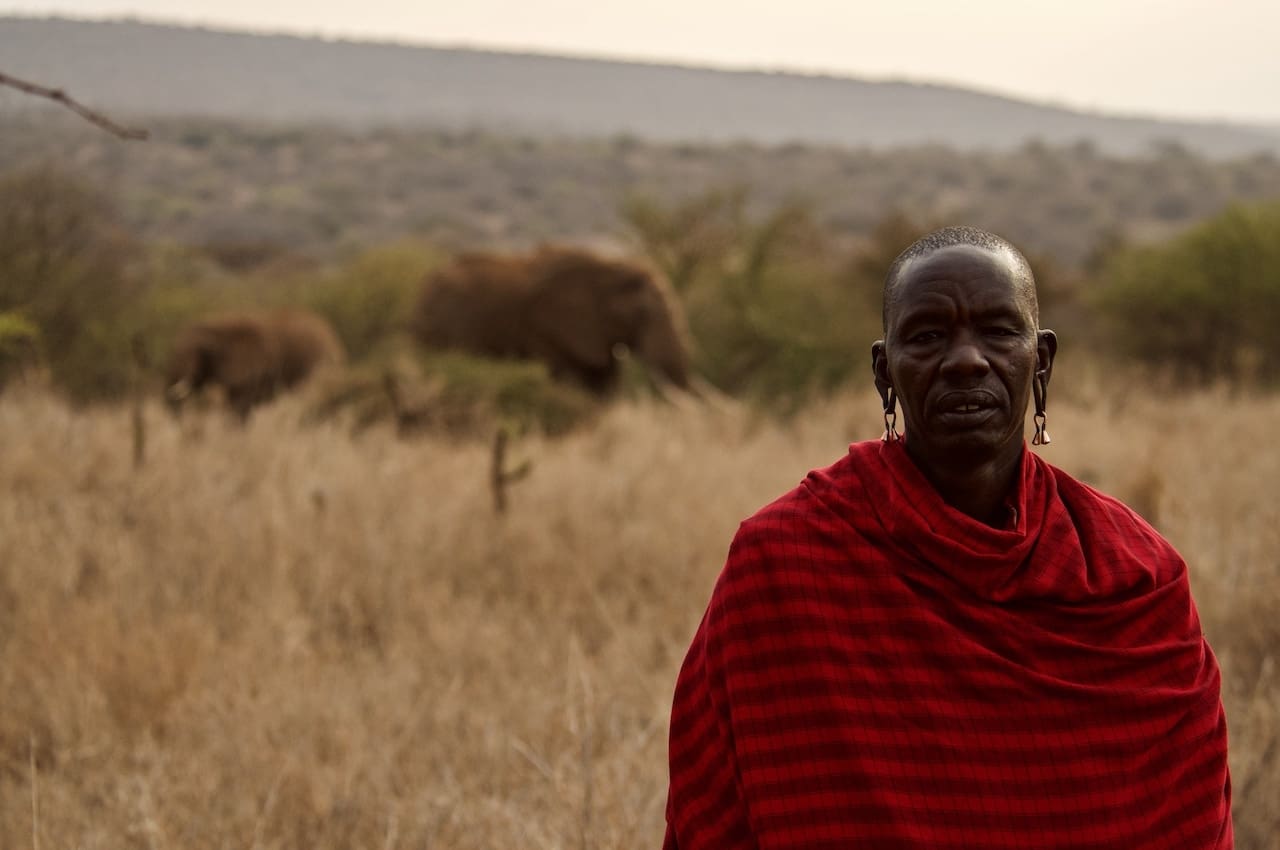 A Masai Mara tribesman in front of wild elephants.